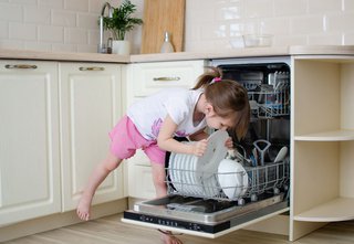 Kind räumt Spülmaschine ein