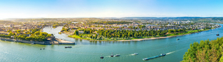 Panoramabild von Koblenz: Man sieht die Flüsse Rhein und Mosel aufeinandertreffen sowie viel vom Stadtbild.