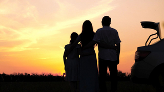 Mutter, Vater Tochter von hinten als Silhouette am roten Abendhimmel beim Sonnenuntergang