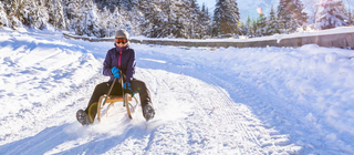 Frau fährt auf dem Schlitten in verschneiter Landschaft