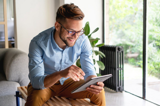 Sitzender junger Mann schaut auf sein Tablet