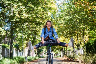 Fröhliche Frau mit Fahrrad auf einer Allee