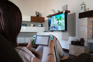 Frau im Wohnzimmer mit Spielekonsole