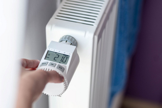 Heizung mit digitalem Thermostat - Hand am Thermostat