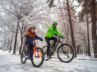 Mann und Kind mit Fahrrad im Schnee