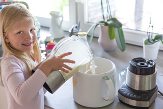 Blondes Mädchen befüllt eine Eismaschine