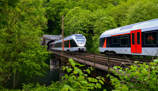 Zwei Züge fahren über eine Brücke, die aus einem Tunnel kommt.