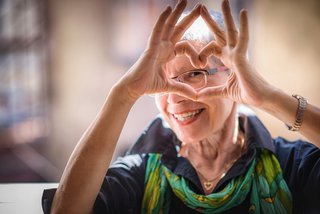 Ältere Frau hält ihre Hände zu einem Herz geformt vor ihr Gesicht