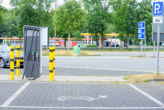 E-Ladestation auf einer Autobahnraststätte, die man im Hintergrund erkennt.