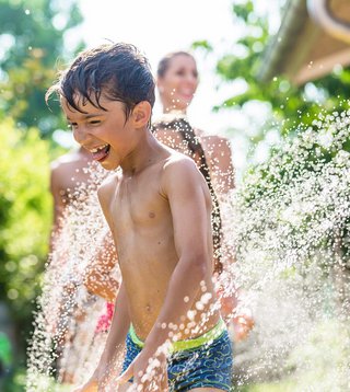 Kinder haben Spaß durch eine erfrischende Gartendusche