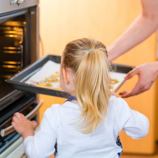 Frau schiebt Plätzchen in den Backofen 