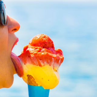 Frau mit Sonnenbrille schleckt Eis