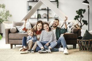 Familie hält Dach aus Pappe über sich